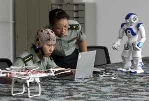 A student and an instructor look at a computer as they demonstrate using a headset to control robots with her mind, at the PLA Information Engineering University, in Zhengzhou
